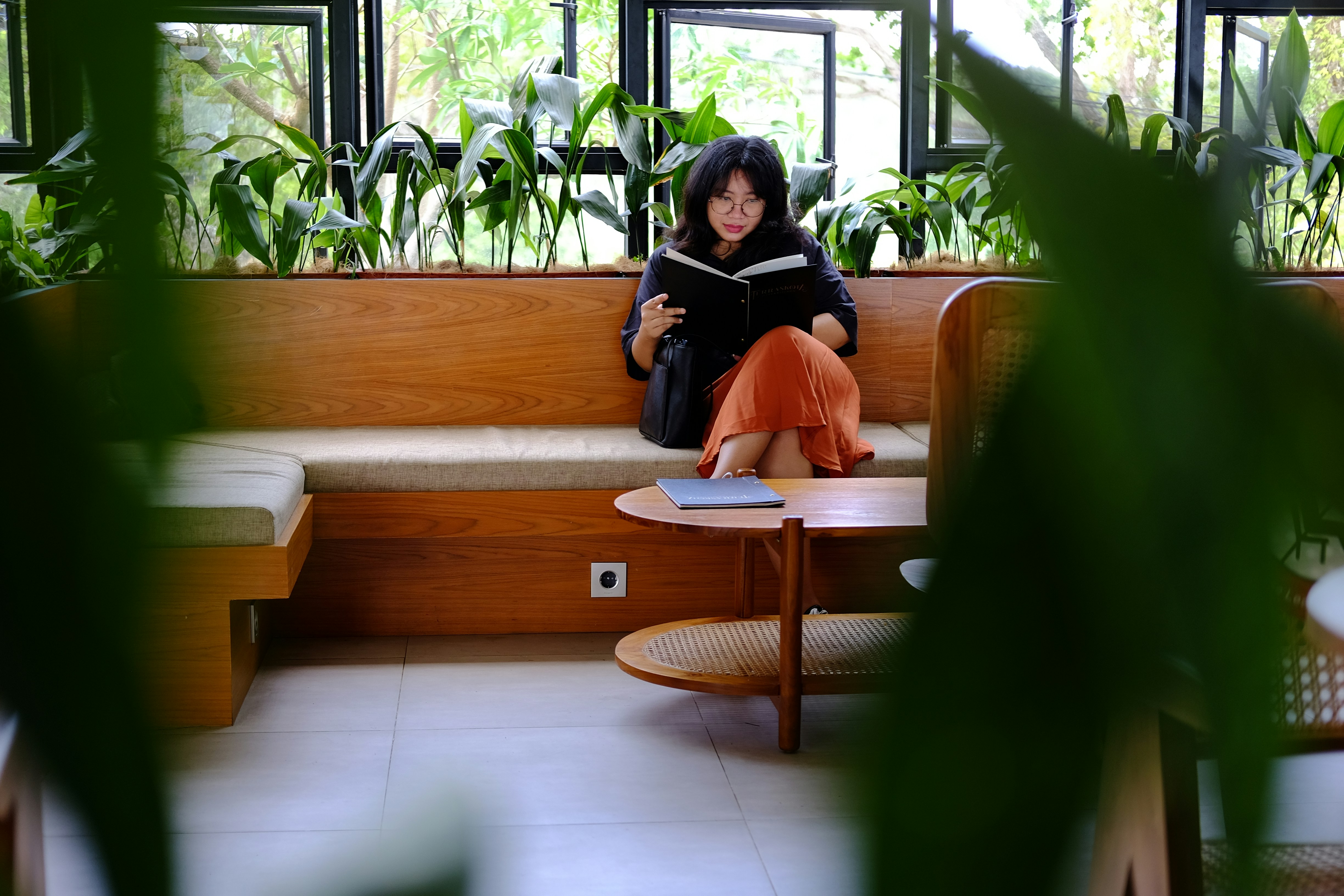 uma mulher sentada em um banco lendo um livro