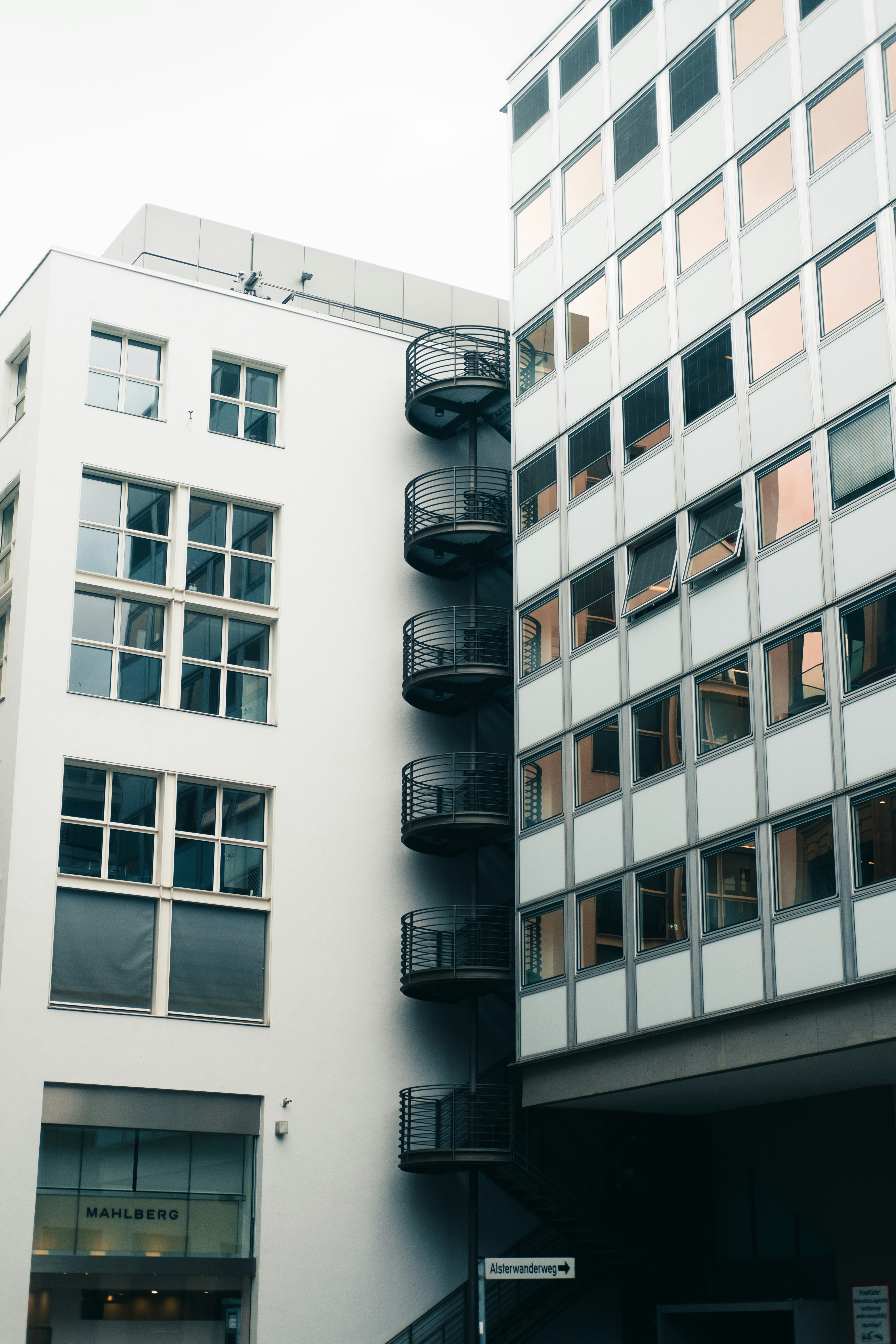 a tall white building next to a parking garage