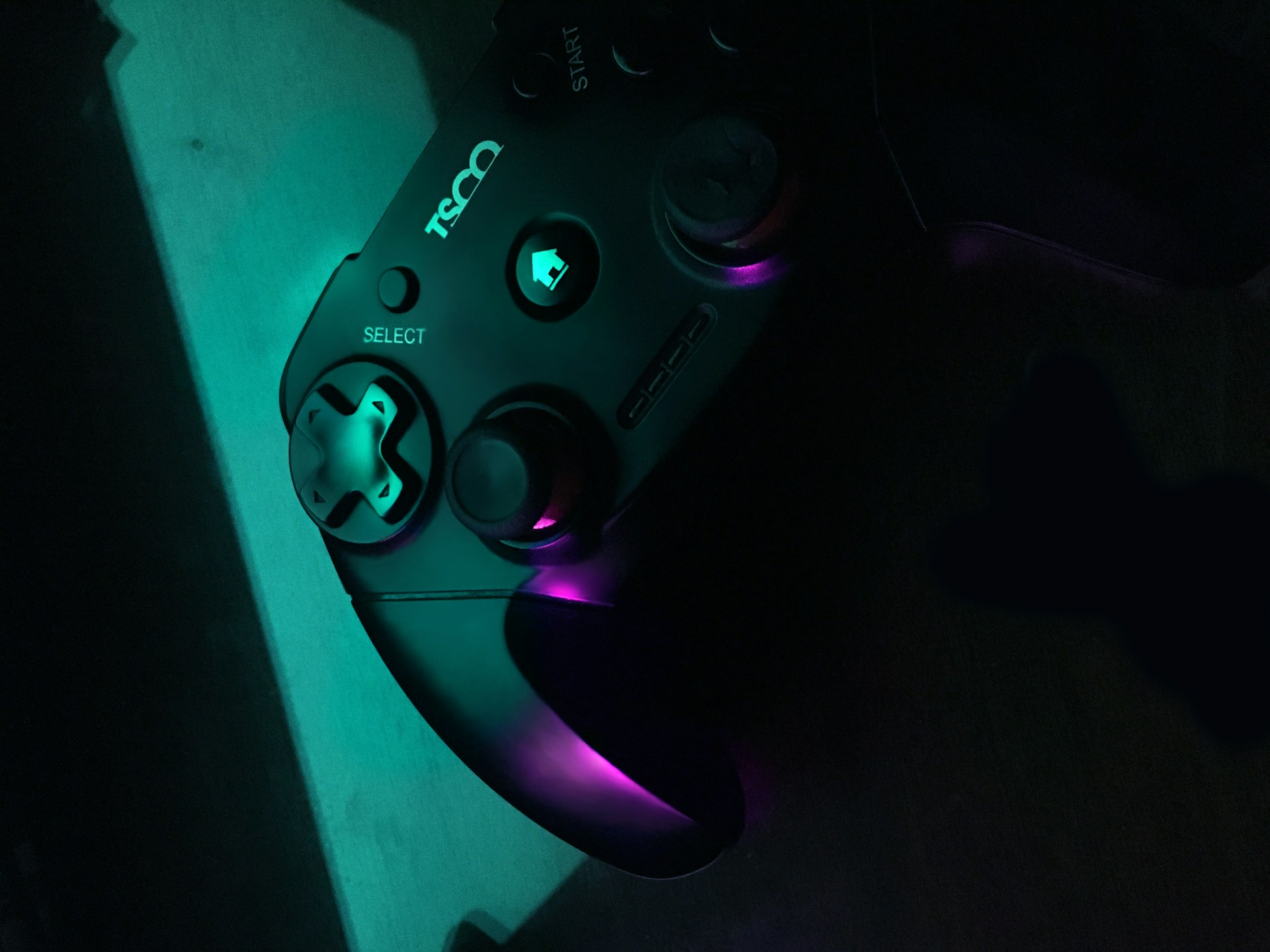 A vibrant, glowing neon purple and electric blue gaming controller resting on a dark navy surface with subtle cyan highlights.