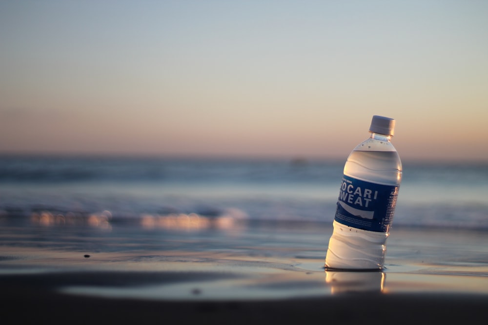 a bottle of water sitting on top of a beach