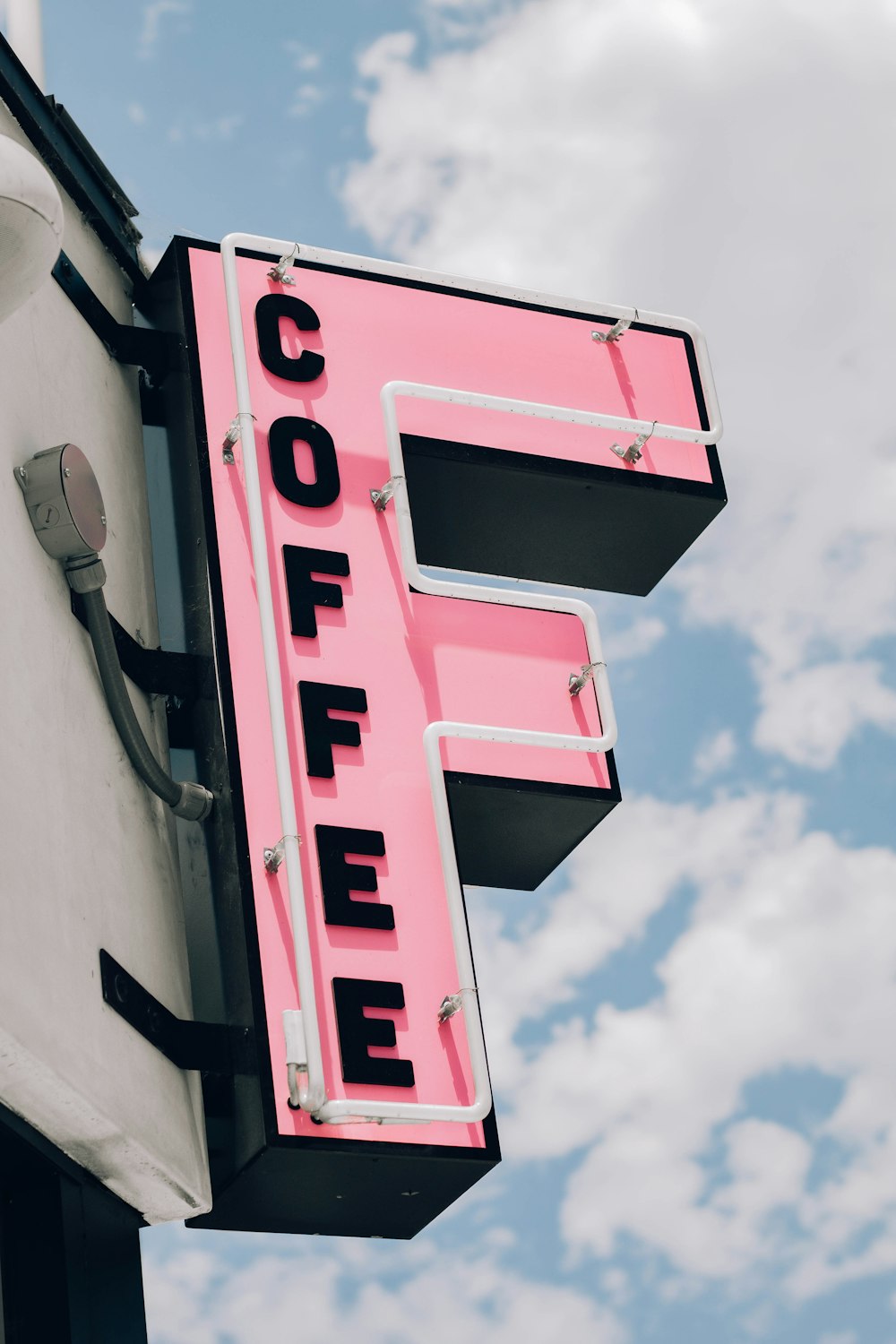 a pink sign that says coffee on the side of a building