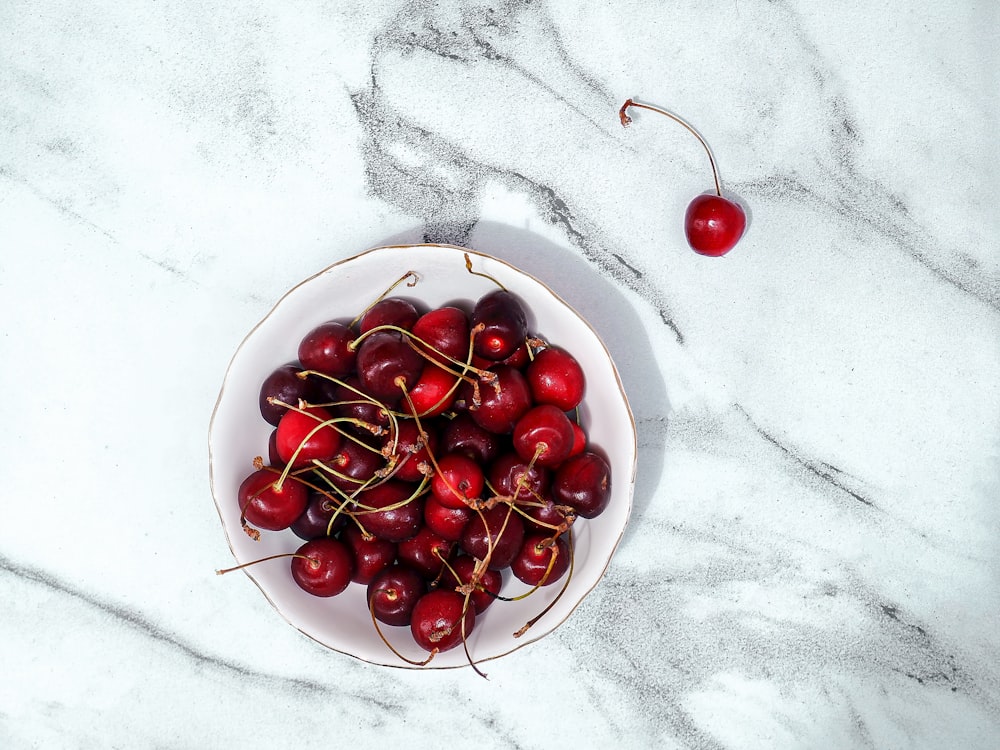 a bowl of cherries on a marble table