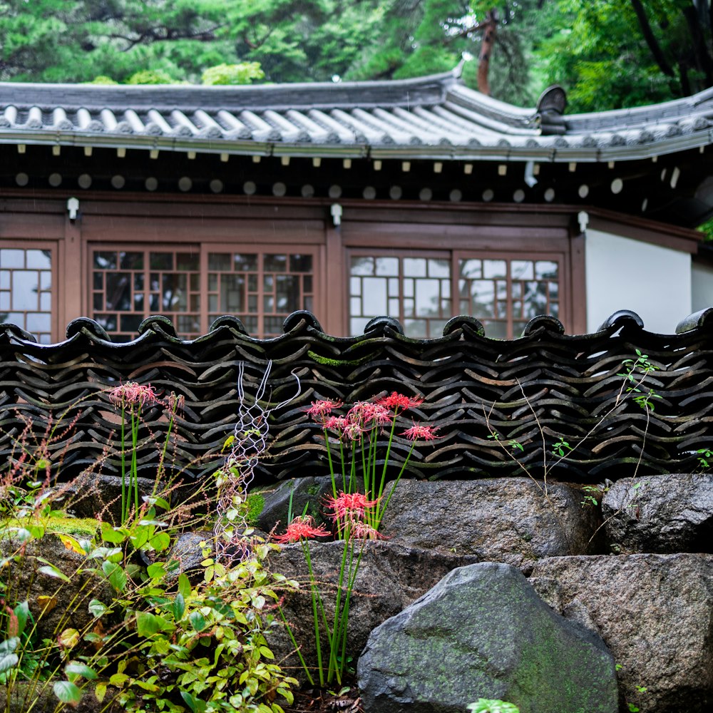 a building with a stone wall and flowers in front of it