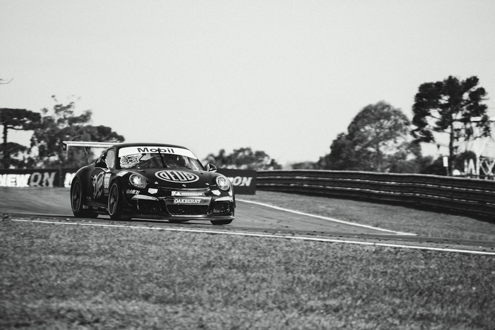 a black and white photo of a car driving on a race track