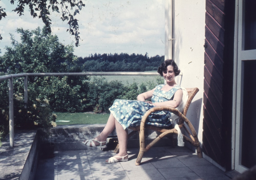 une femme assise sur une chaise sur un porche