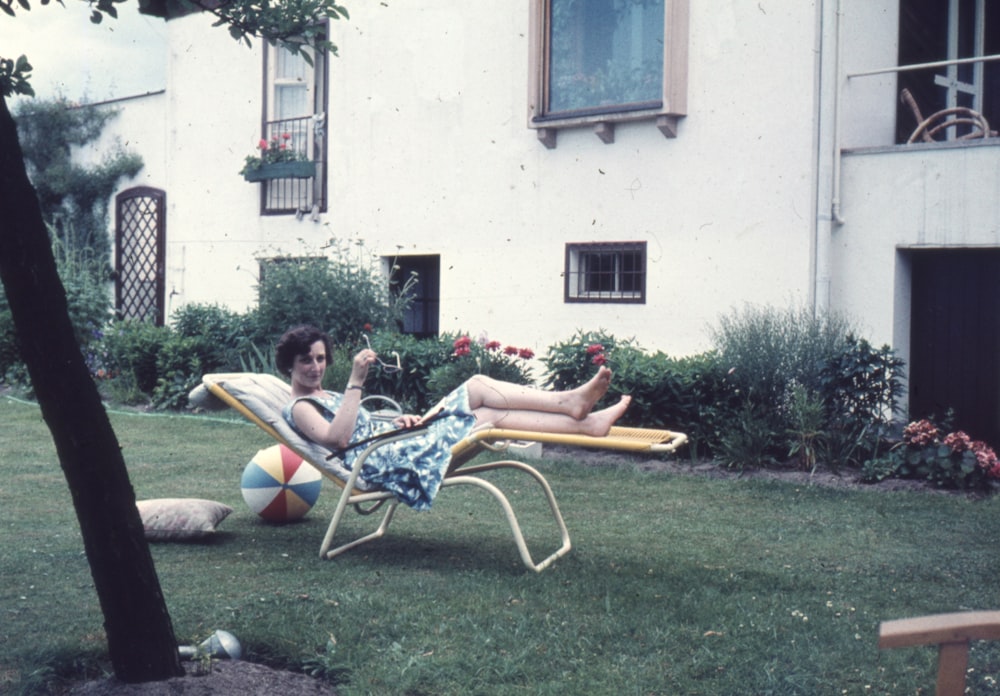 a woman laying on a lawn chair in a yard