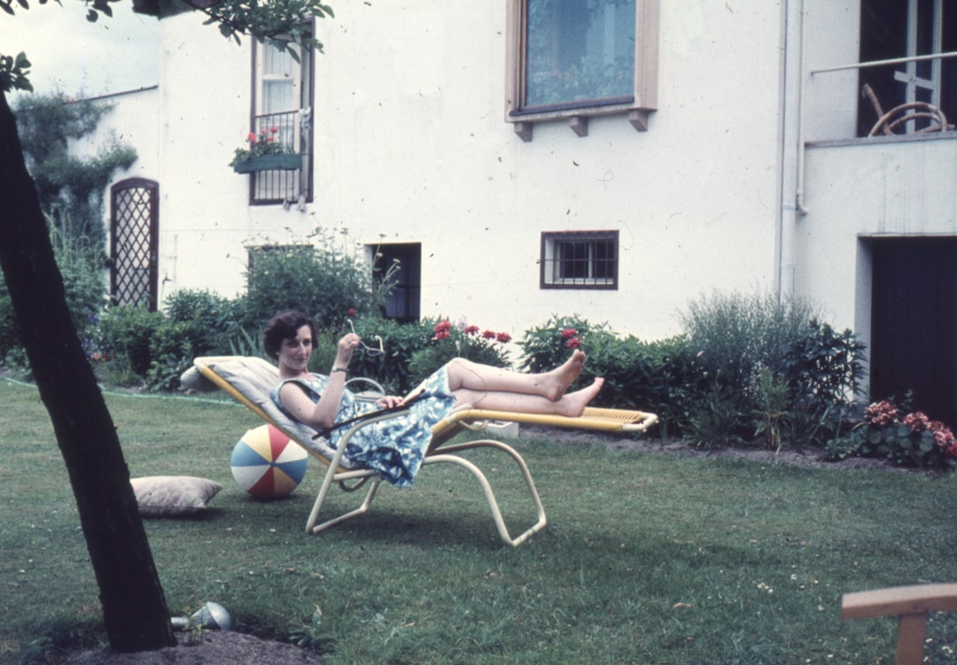 a woman laying on a lawn chair in a yard, Taken in June 1960