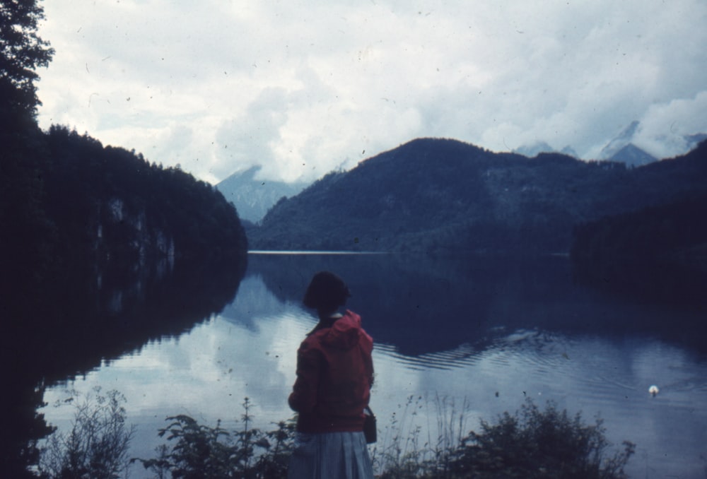 uma pessoa de pé em uma colina com vista para um lago