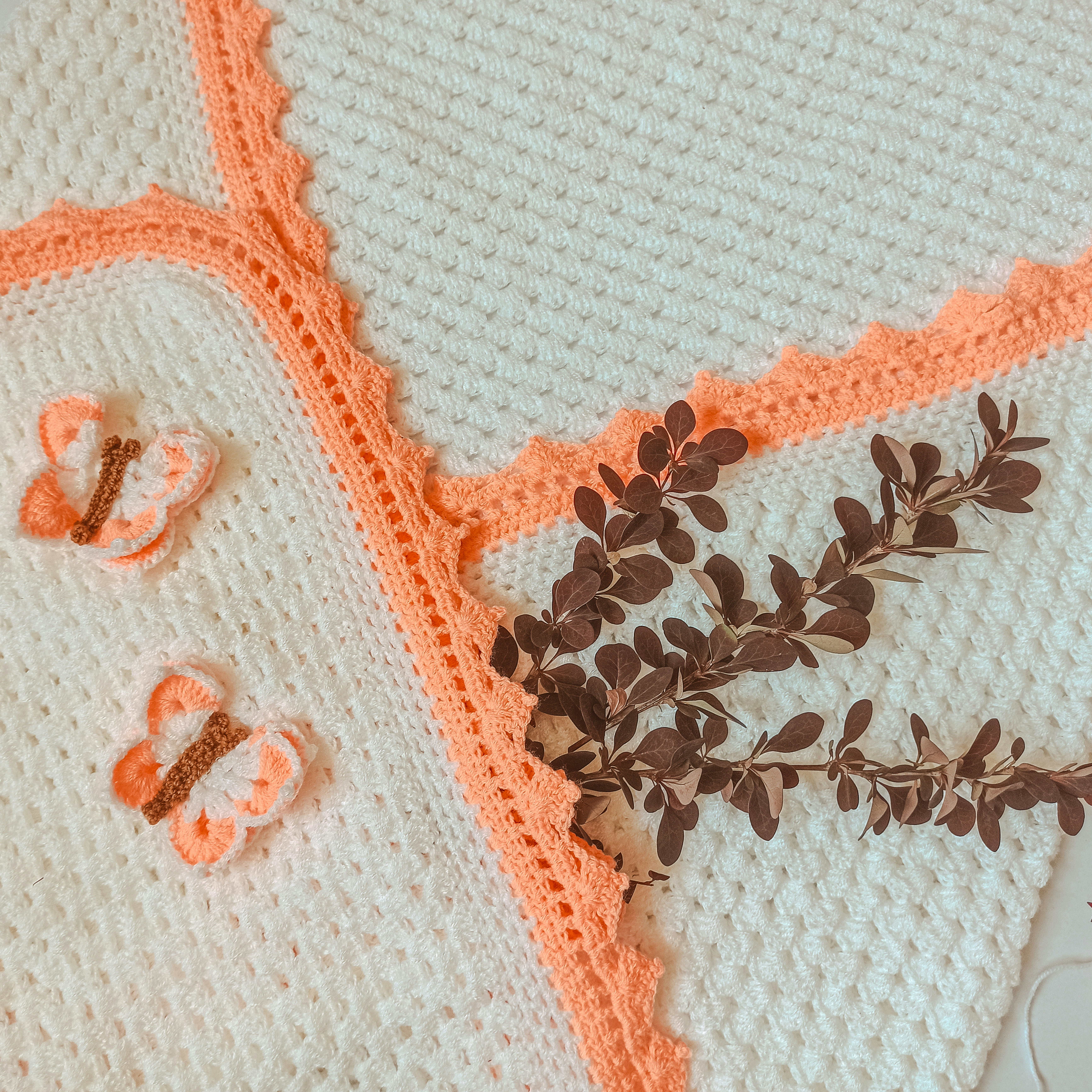 a crocheted blanket with a plant on top of it