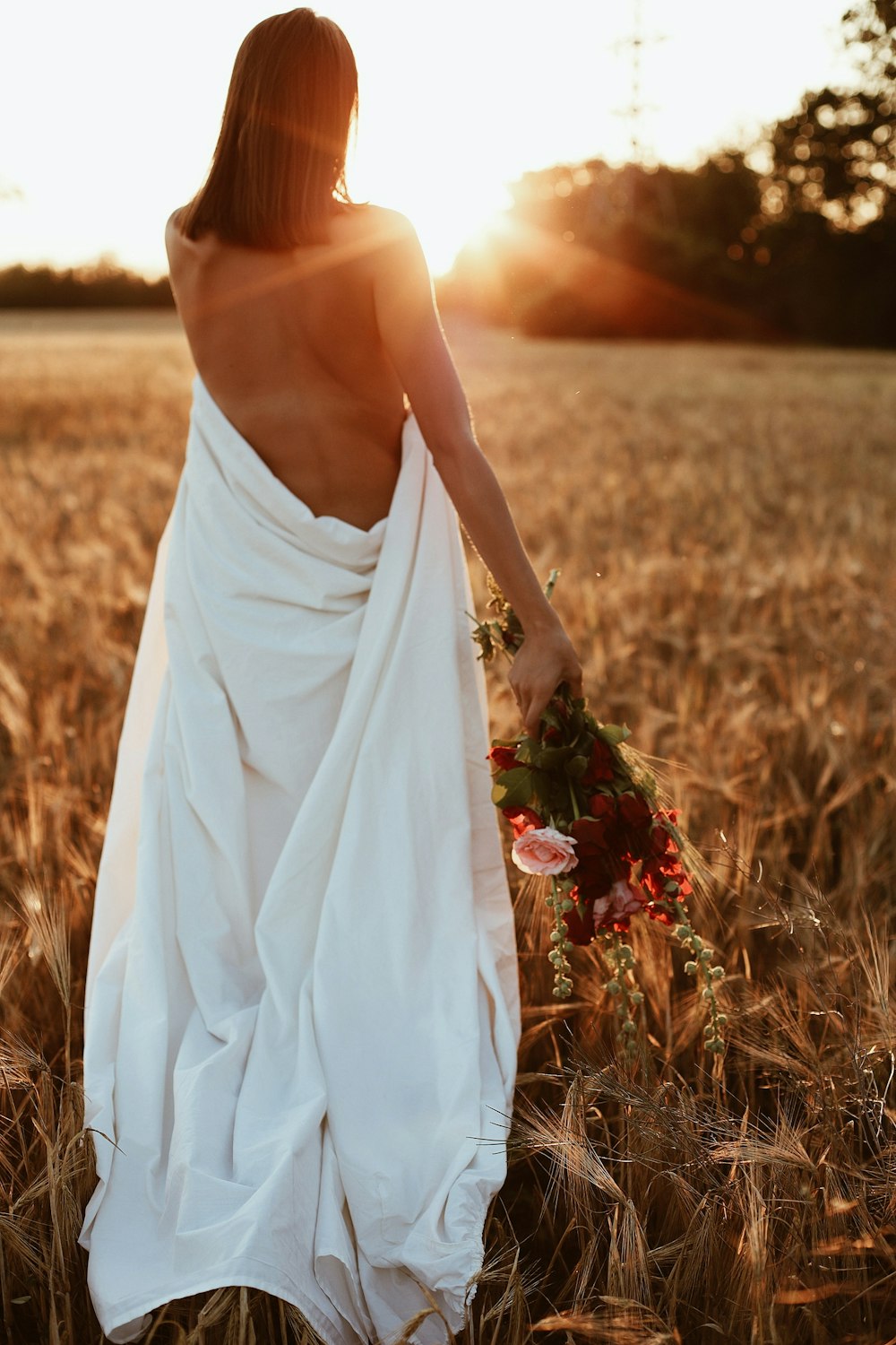 a woman in a white dress walking through a field