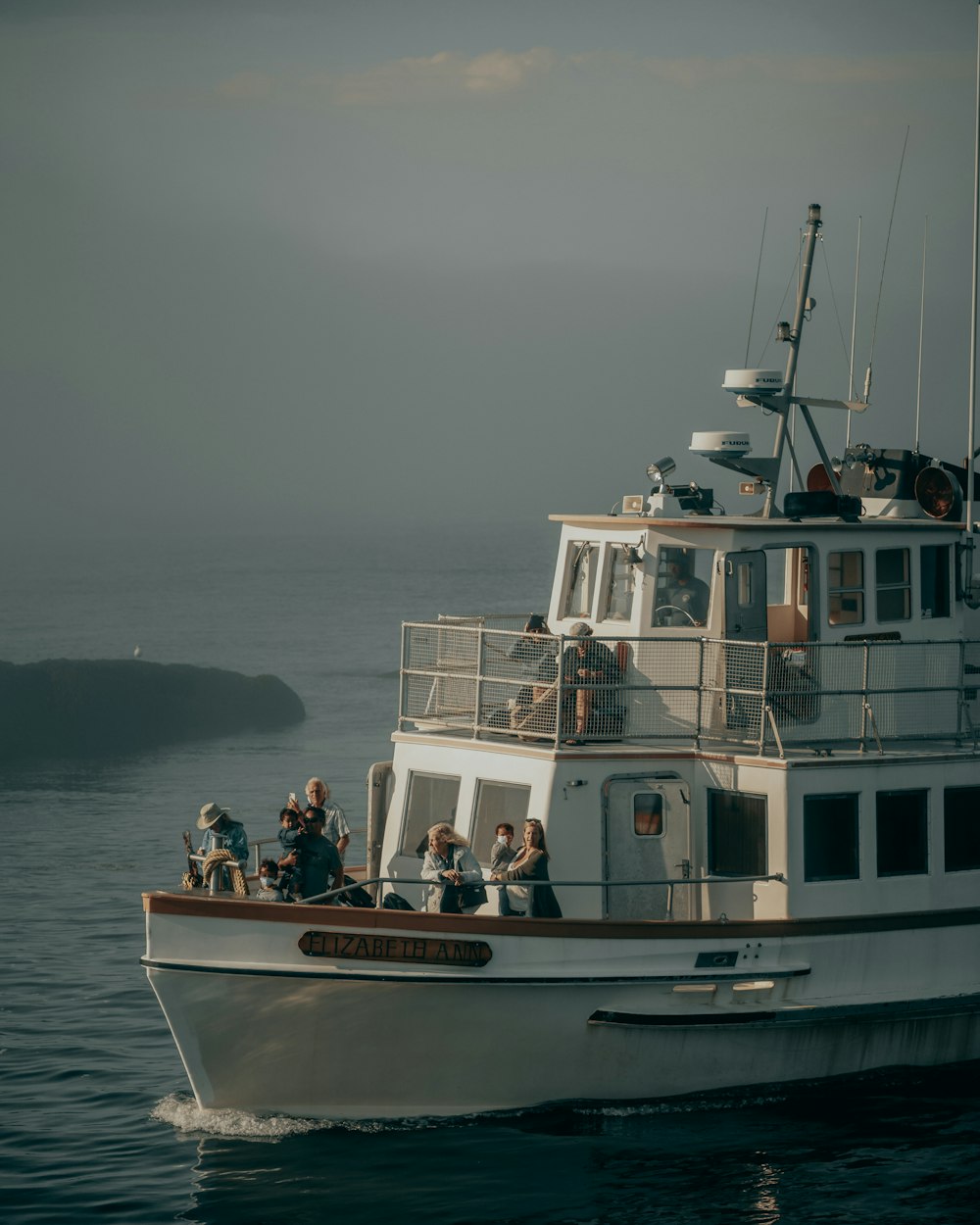 a white boat with people on it in the water