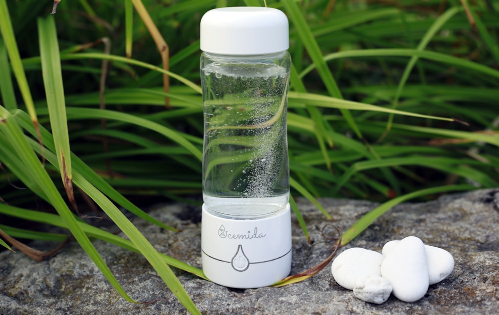 a glass bottle with water inside sitting on a rock