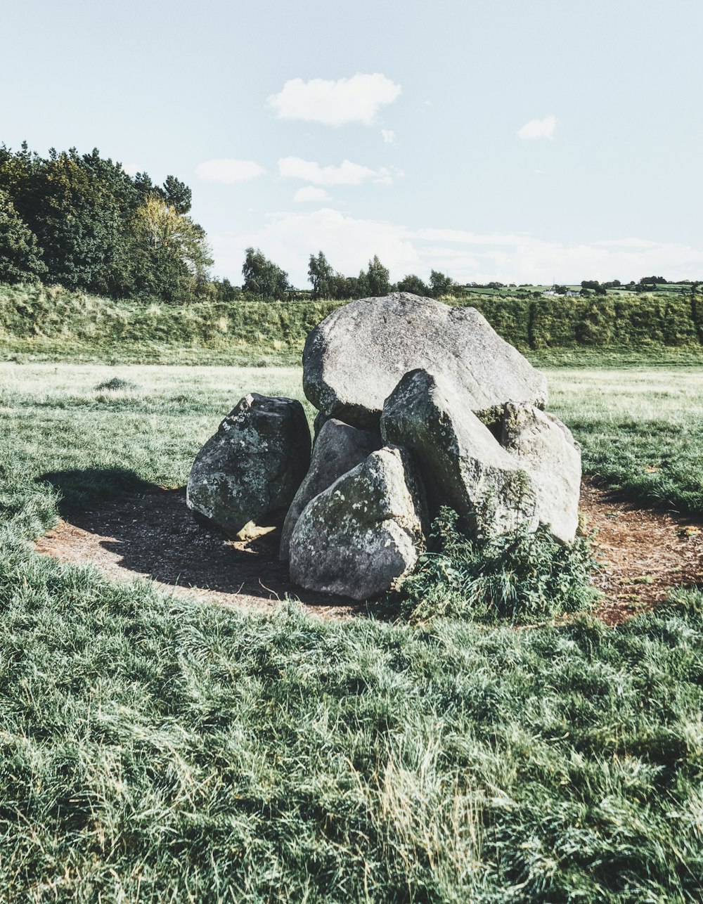 a large rock sitting on top of a lush green field