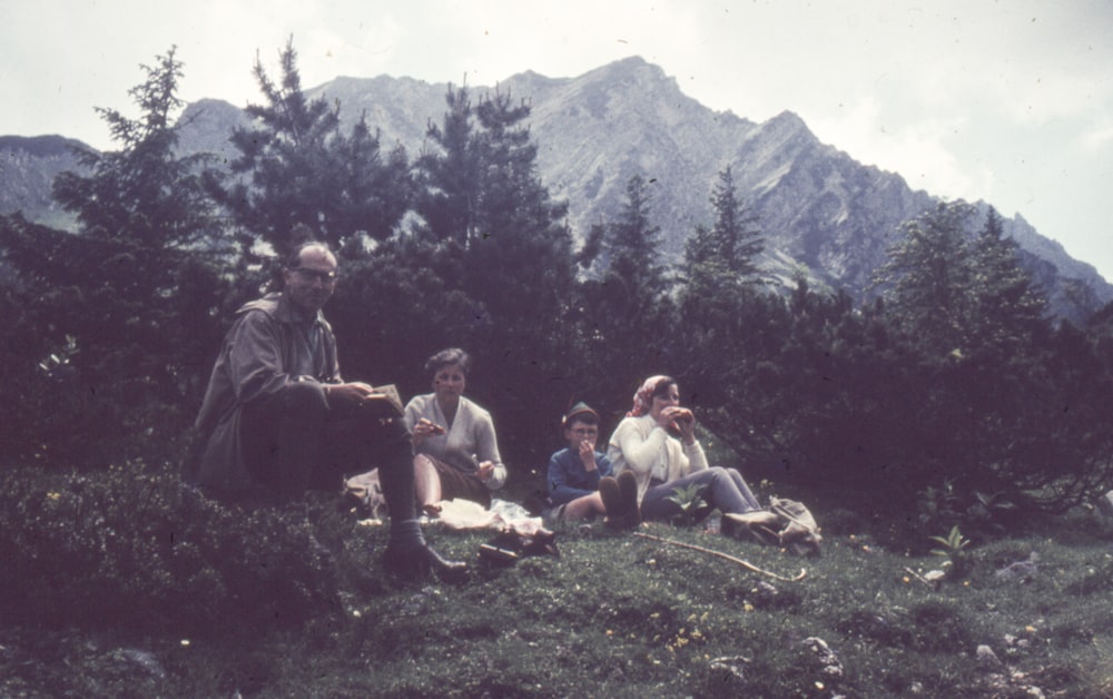 Un grupo de personas sentadas en la cima de una exuberante ladera verde