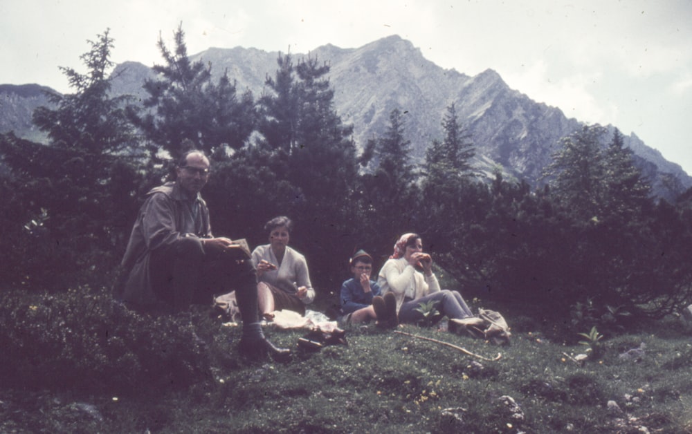 a group of people sitting on top of a lush green hillside