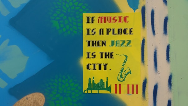 A colorful poster with the text 'If music is a place, then jazz is the city' in various fonts. The poster has illustrations of a saxophone, a city skyline, and decorative patterns in the background. The background is a bright mix of blue, green, and yellow with some abstract shapes.