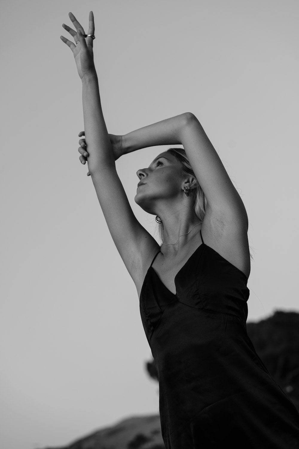 a woman in a black dress reaching up to catch a frisbee