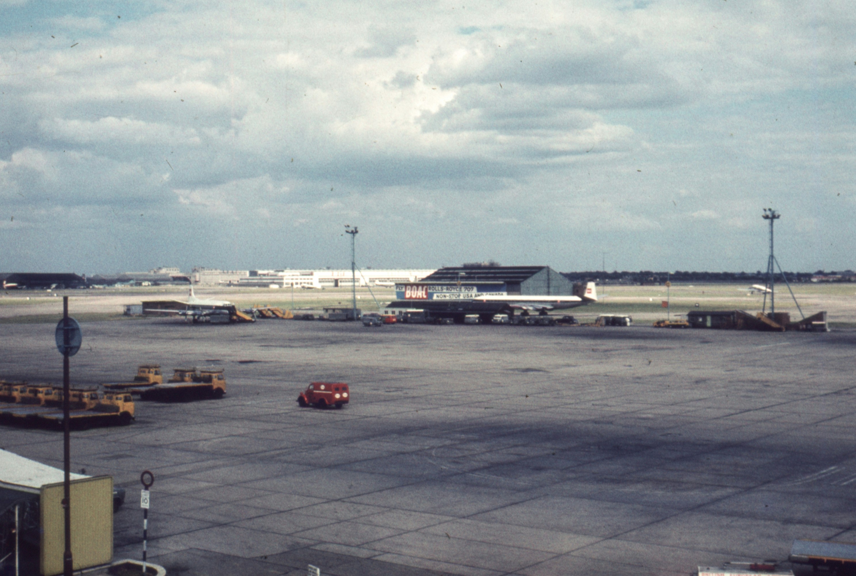 an airport tarmac with an airplane parked on the tarmac, London airport 1960
