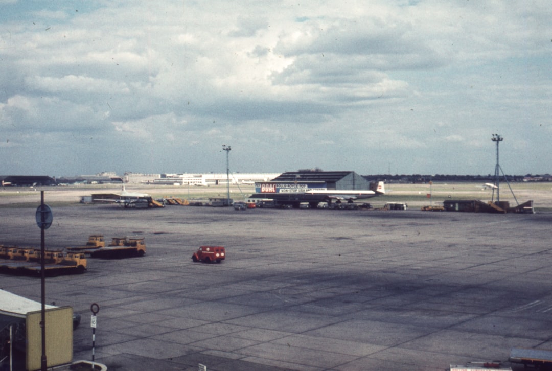 an airport tarmac with an airplane parked on the tarmac, London airport 1960
