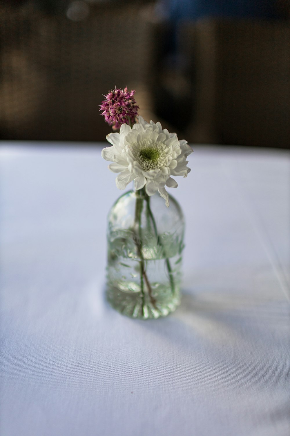 um pequeno vaso de vidro com flores nele