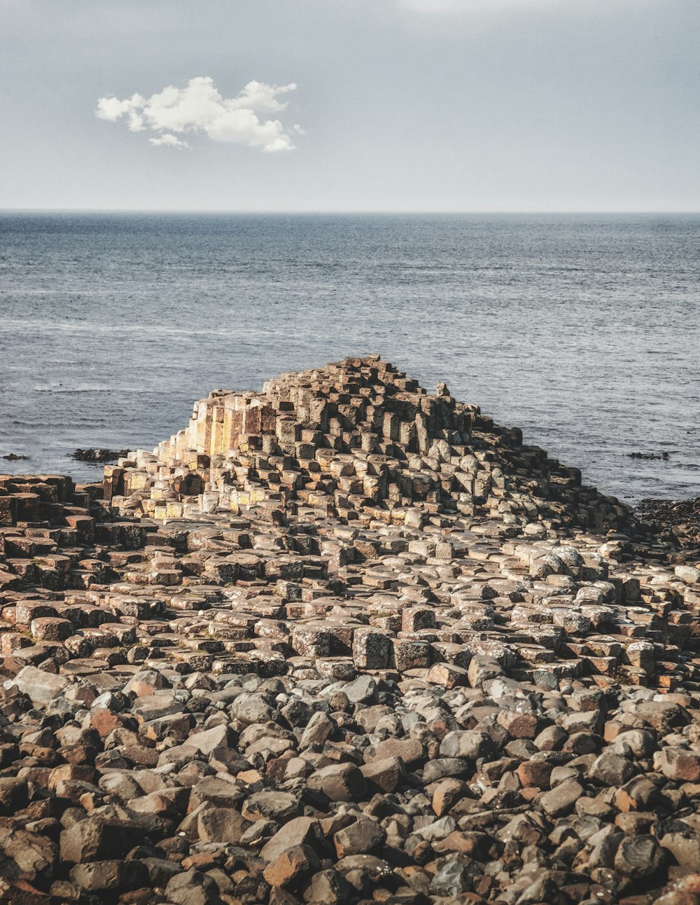un grande mucchio di rocce seduto sulla cima di una spiaggia