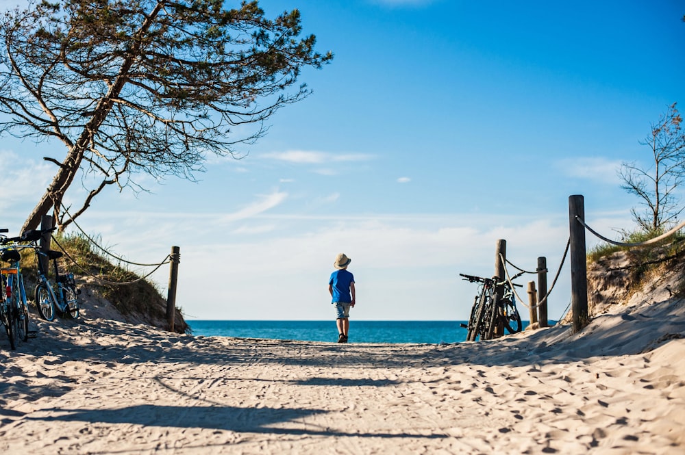 a person standing on a beach next to bicycles