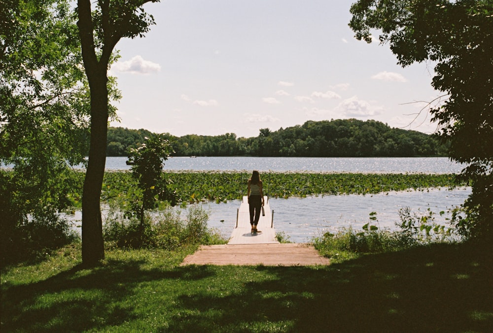 a person standing on a dock near a body of water