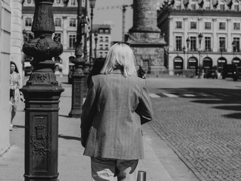 a woman walking down a street past a tall building