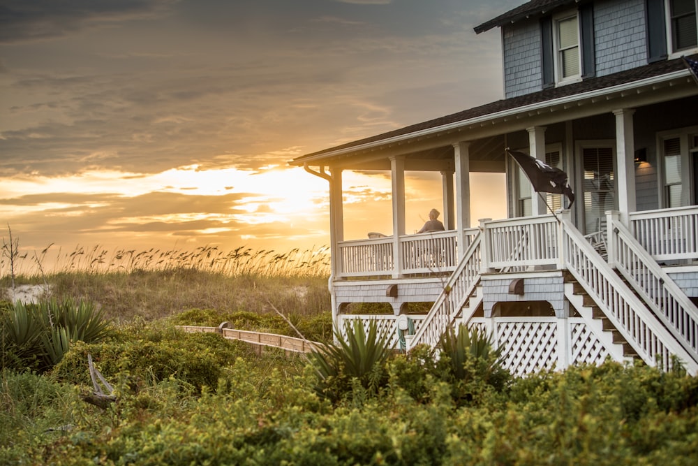 a house on the beach with a sunset in the background