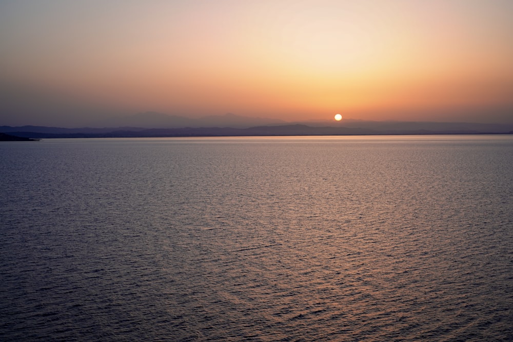 a large body of water with a sunset in the background