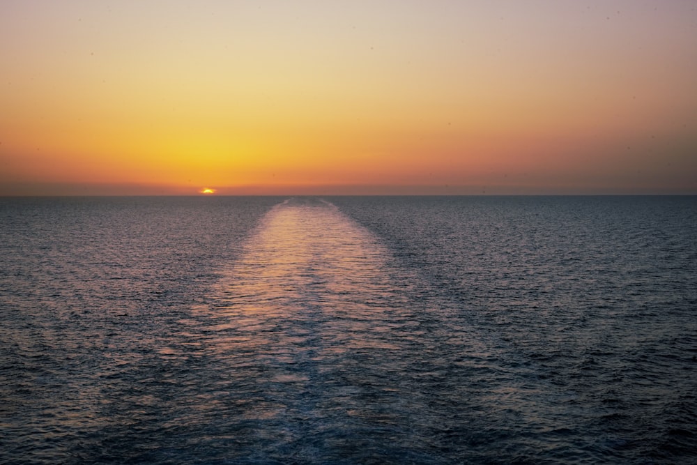 the sun is setting over the horizon of a body of water