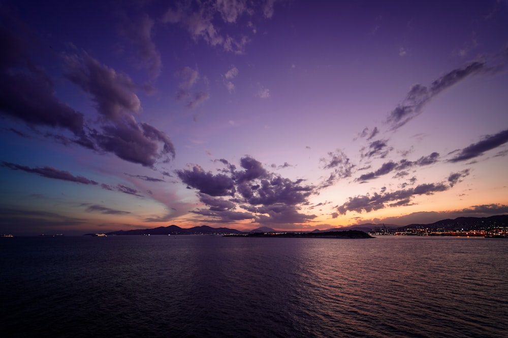 a sunset over a body of water with mountains in the background