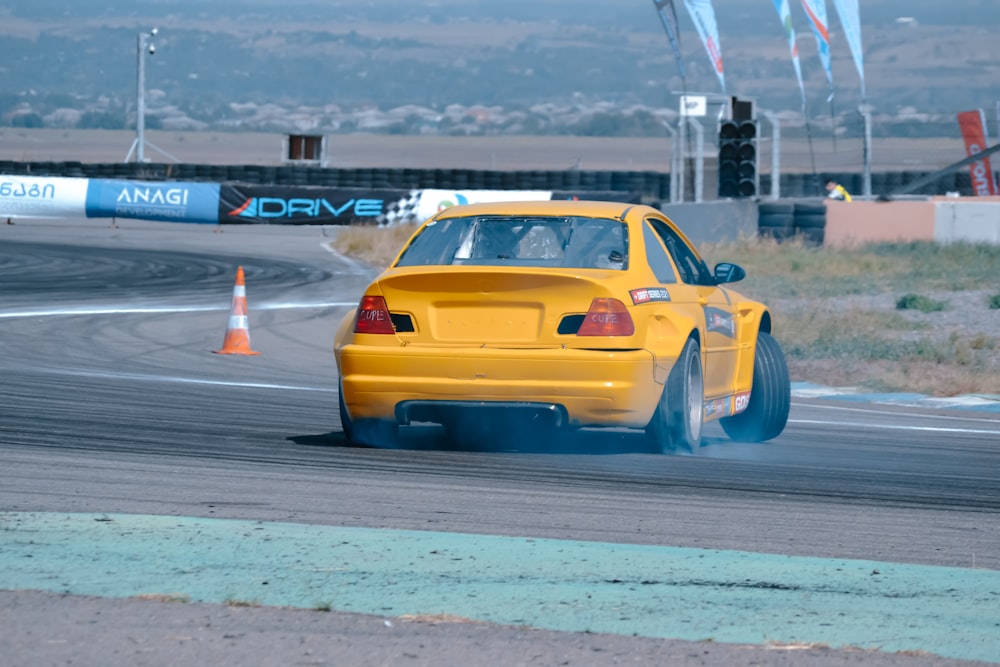 a yellow car driving down a race track