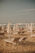 a group of lawn chairs sitting on top of a sandy beach