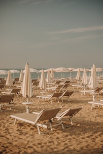 a group of lawn chairs sitting on top of a sandy beach
