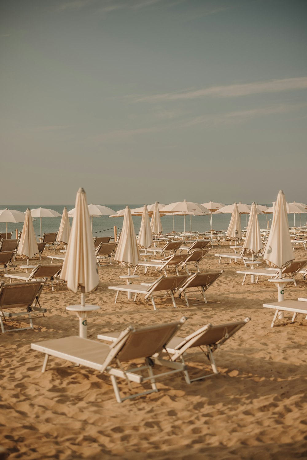 a group of lawn chairs sitting on top of a sandy beach