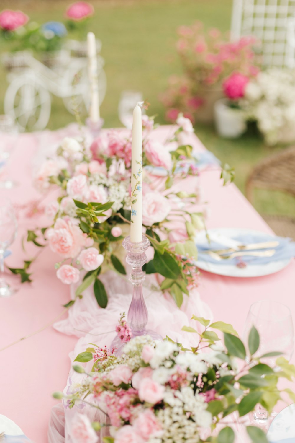 a long table with pink and white flowers and candles