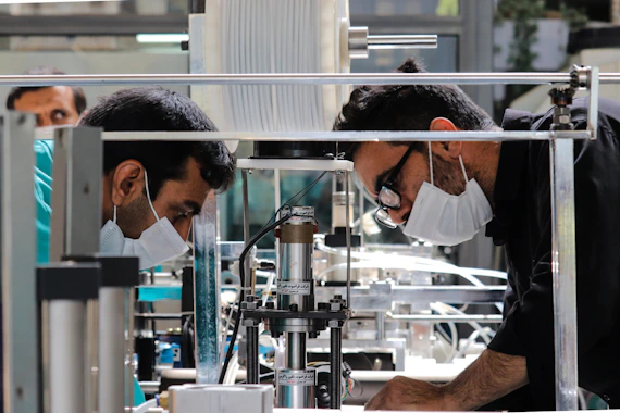 two men in masks working on a machine