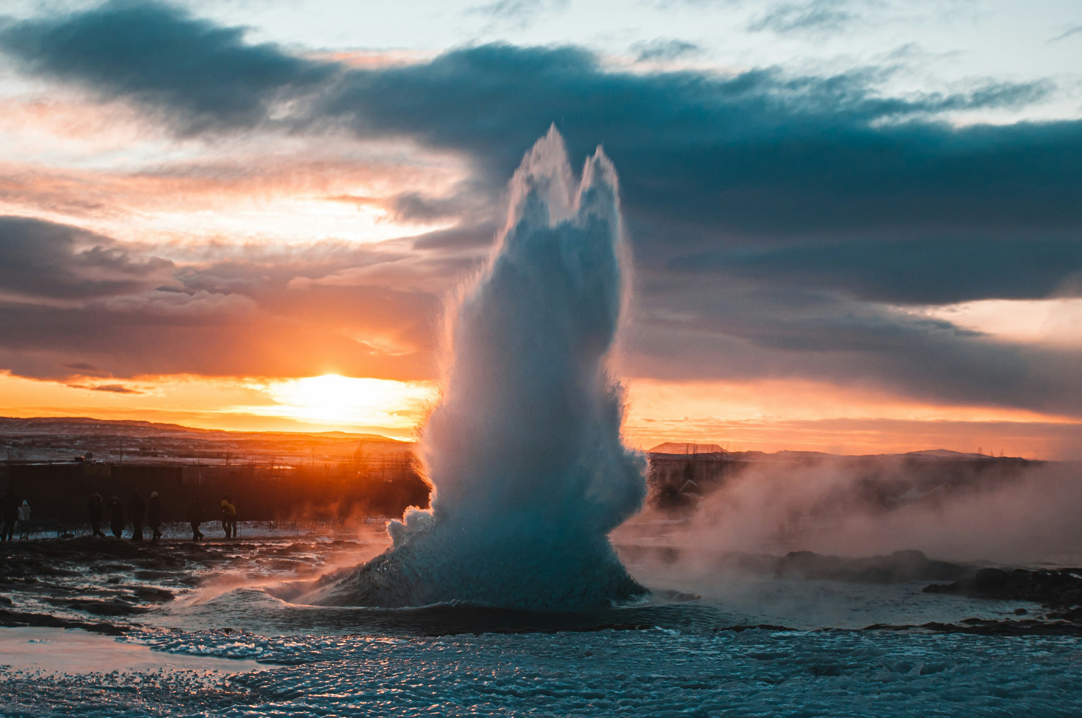 a geyser spewing water into the air at sunset, 