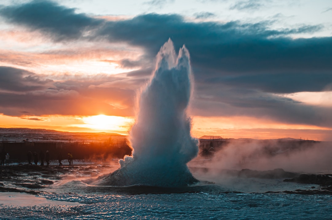 a geyser spewing water into the air at sunset,