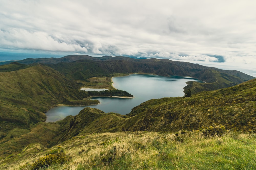 a large body of water sitting on top of a lush green hillside