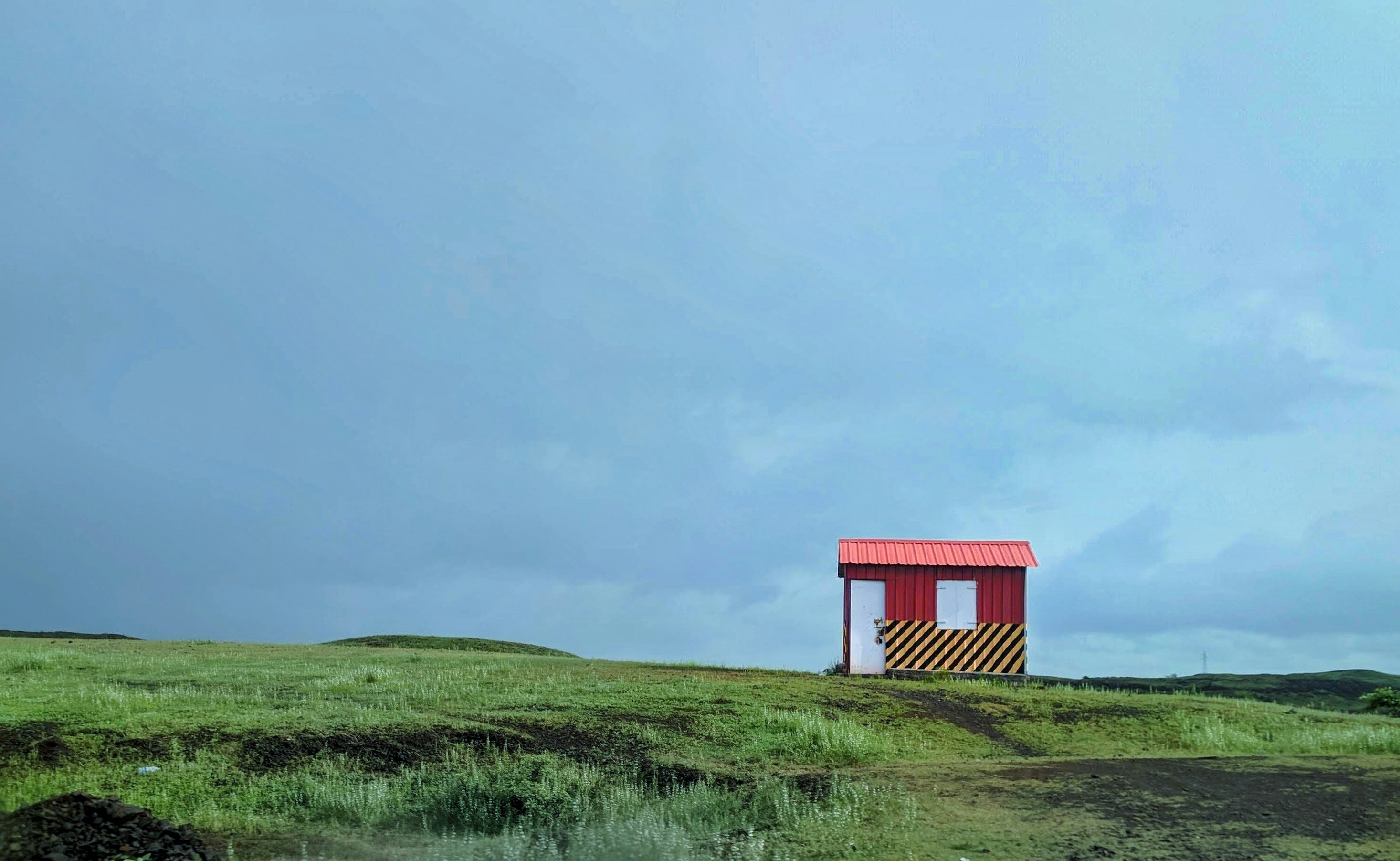 a small red structure sitting on top of a lush green field