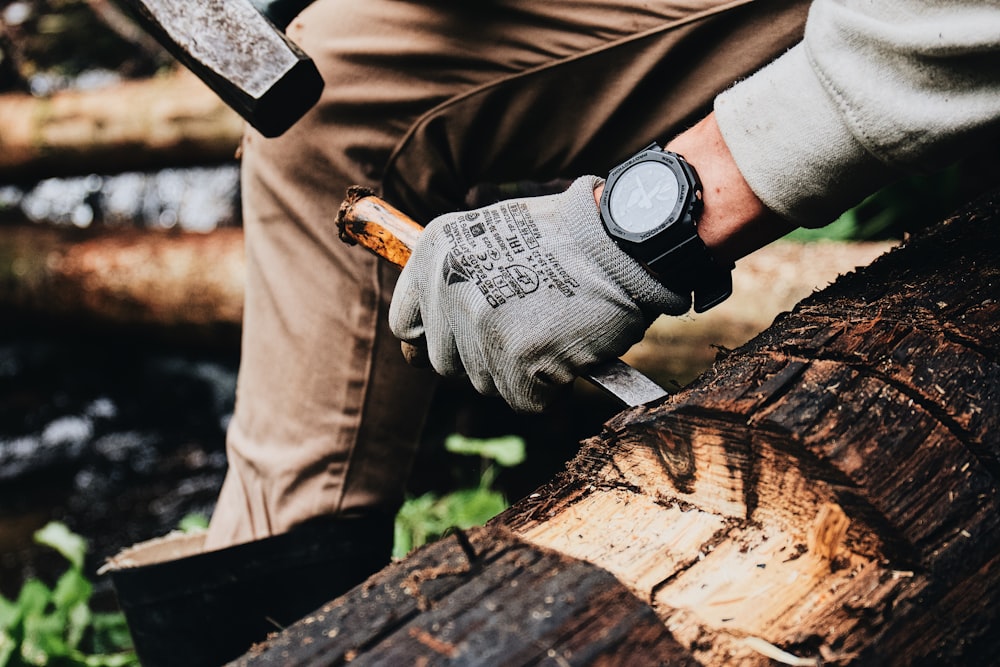 a man is holding a large knife and a log