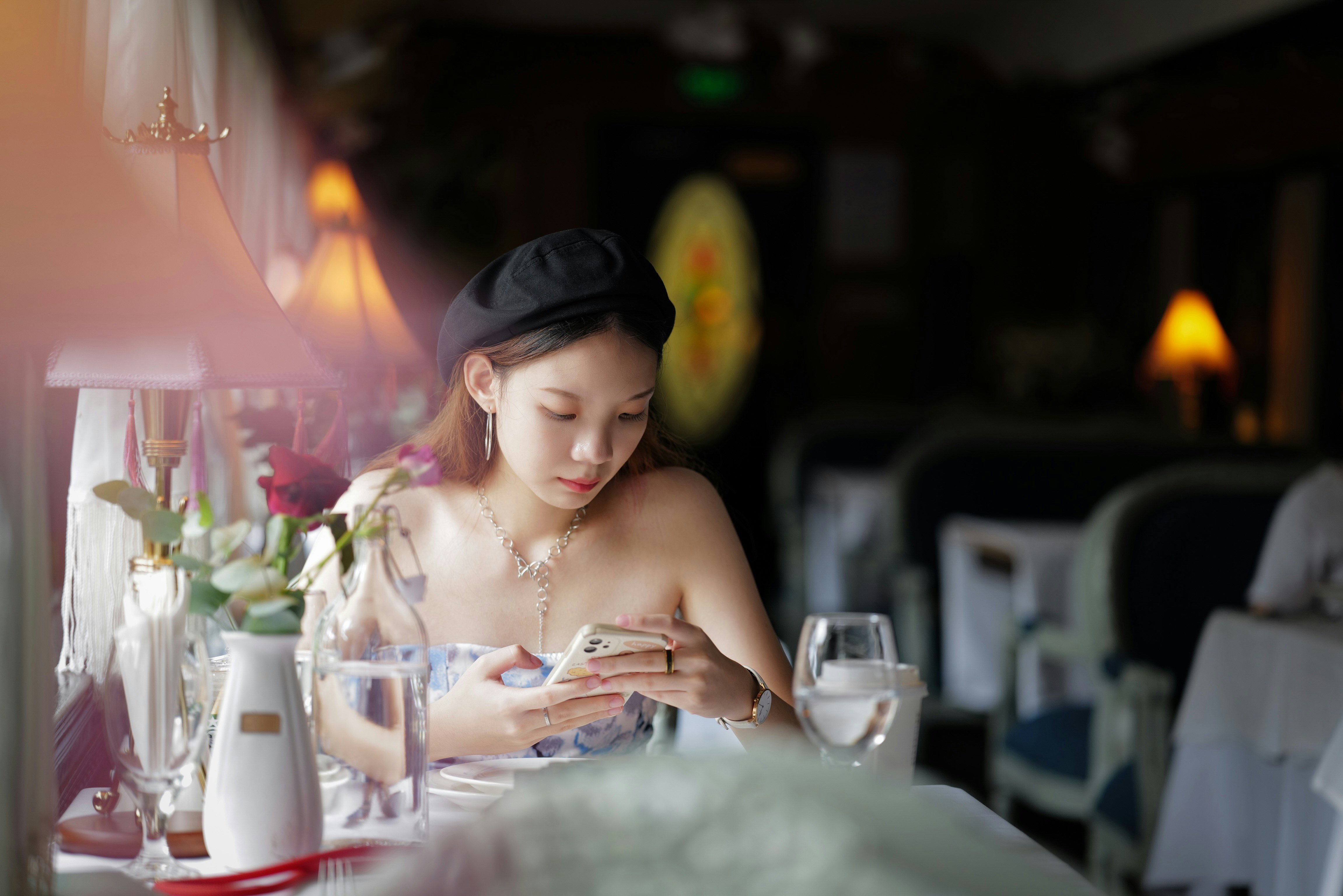 a woman sitting at a table looking at her cell phone