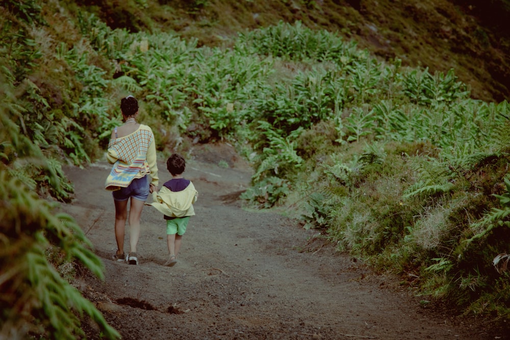 a woman and child walking down a dirt path