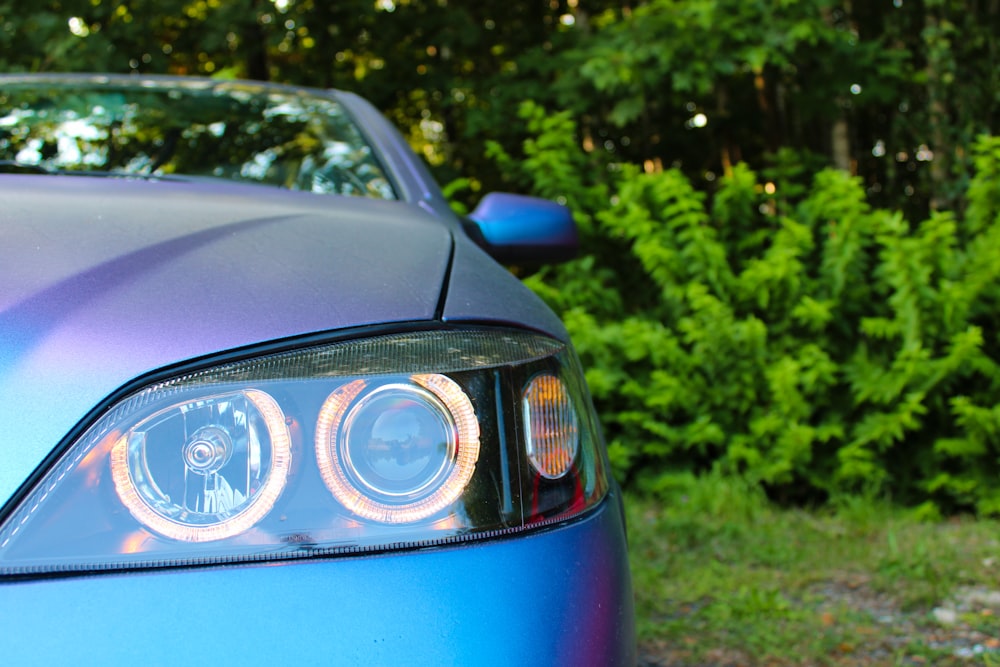 a close up of a car's headlight with trees in the background