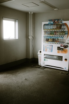 a vending machine sitting in a room next to a window