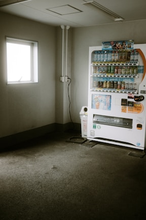 a vending machine sitting in a room next to a window