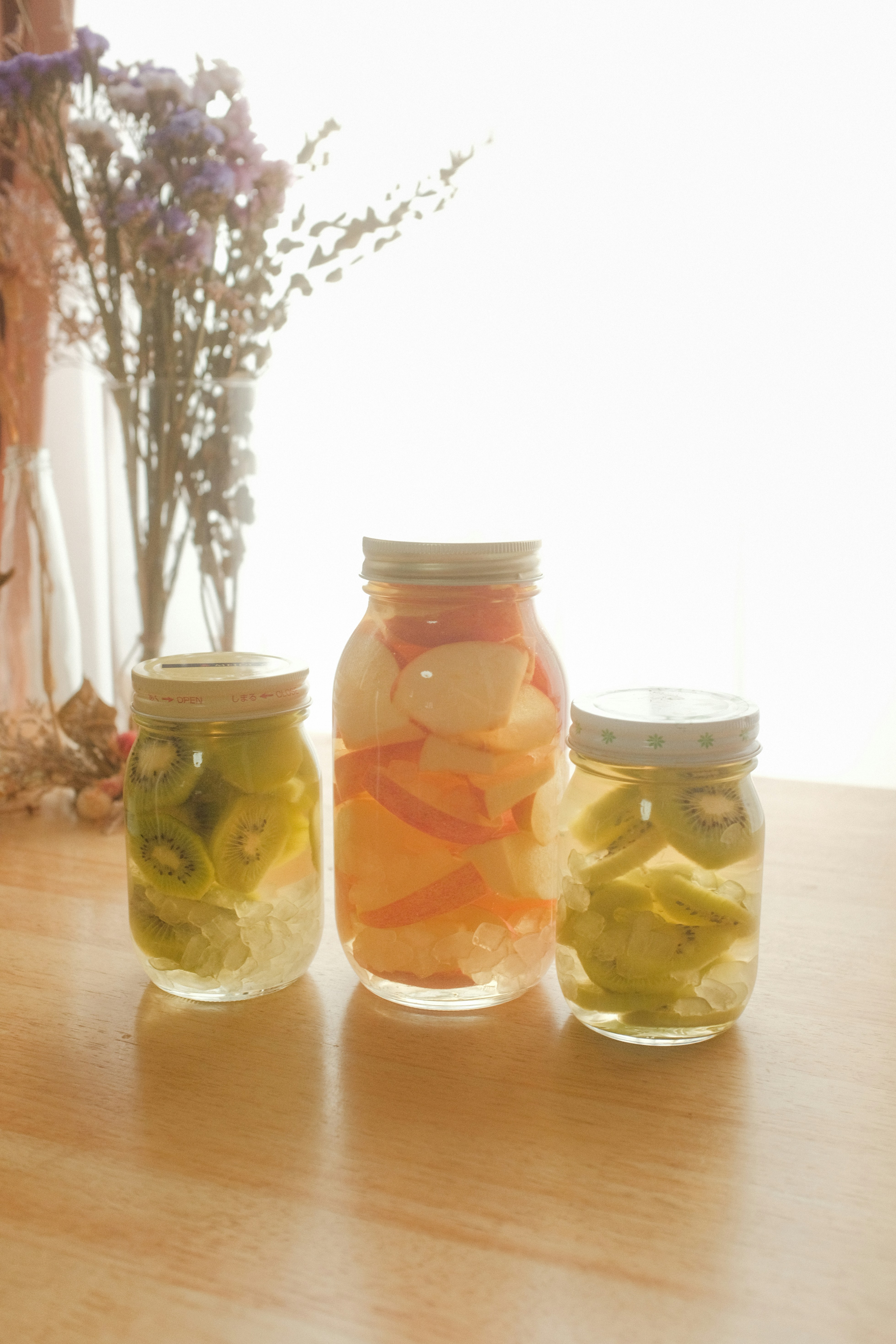 three jars filled with pickles sitting on a table