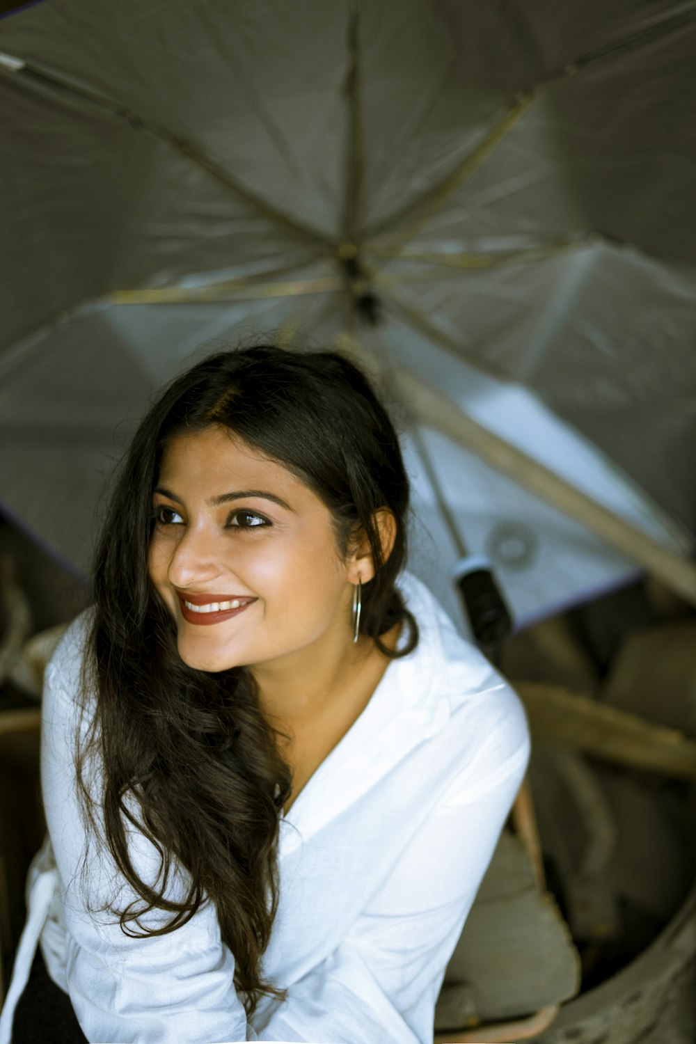 a woman sitting under an umbrella smiling for the camera